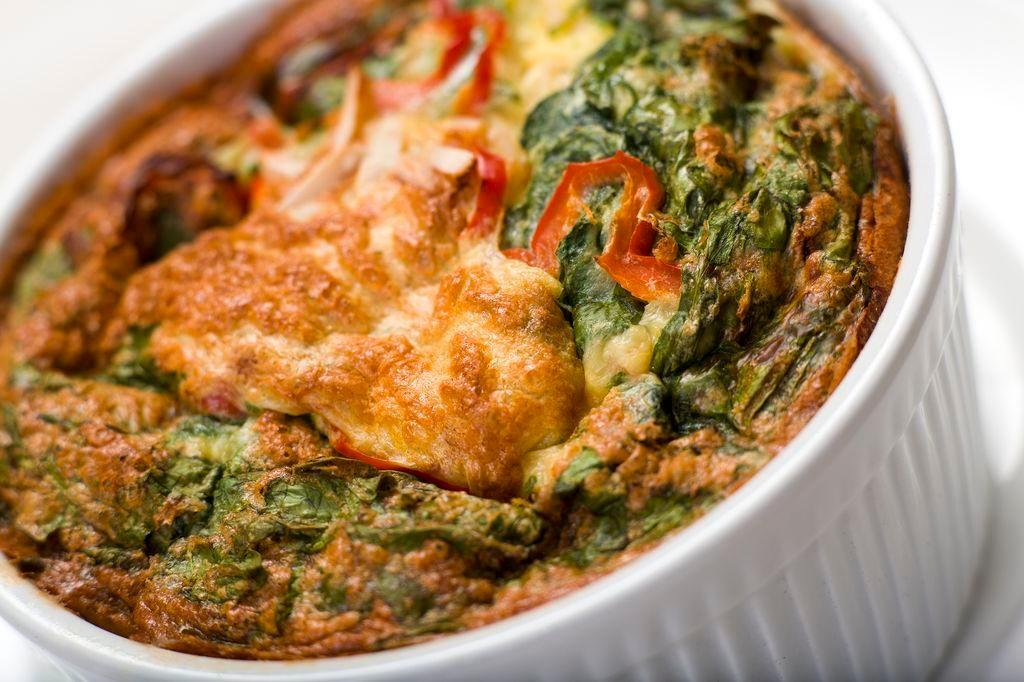 Baked eggs with chopped spinach, garlic, onion and red bell peppers