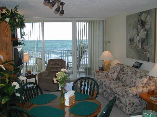 living room with full glass opening to balcony overlooking the heated pool and ocean.