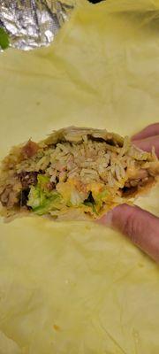 Burrito filled with rice and beans, hardly any meat.