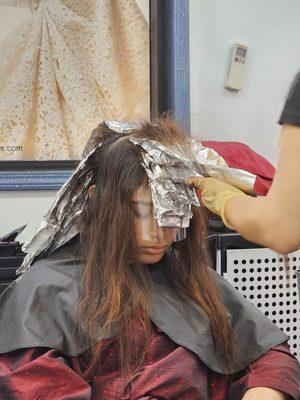 This is the bleaching process... this does take a while to do. You need to be patient during this process. She is on her phone and relaxing.