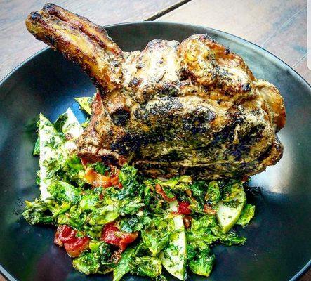 Heritage farms porkchop, 18 oz, served over a brussel leaf, housemade bacon, pear, cambazola vinaigrette salad.