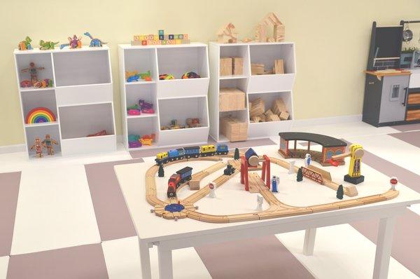 play stations with train tables, large blocks, and other toys.