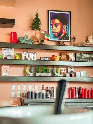 Shelves with art, items, signs and an art piece of Chadwick Boseman!