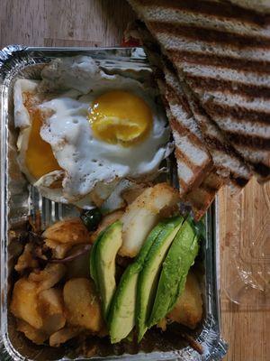 Two eggs, toast, avocado and home fries.