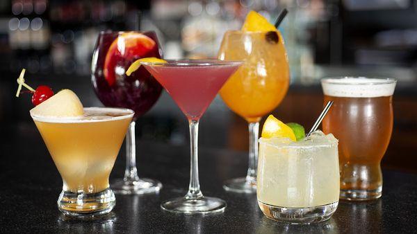 Assorted cocktails lined up along the bar.