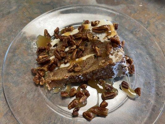 Carrot cake topped with candied pecans and drizzled with caramel sauce.