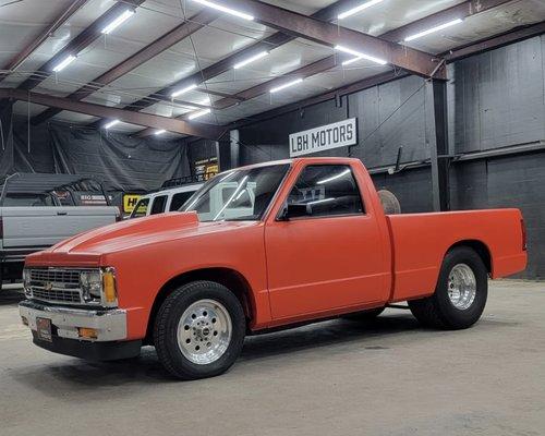 Chevy S10 fresh out of the paint booth with a matte orange job and spray on bedliner.