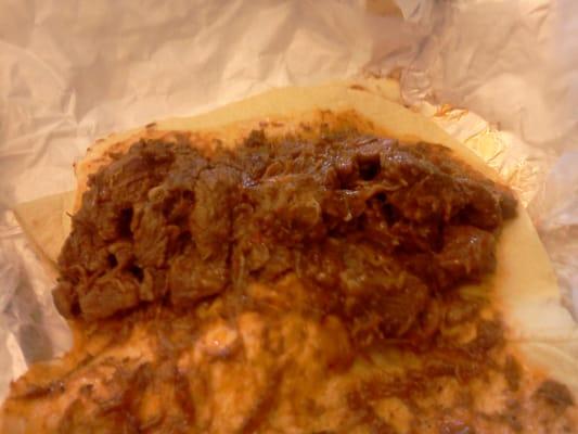 This is a taco of carne guisada in a flour tortilla. The taco tastes very good.