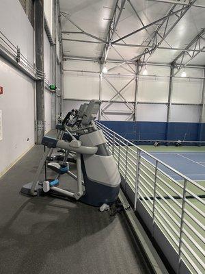 Workout machines upstairs overlooking tennis courts