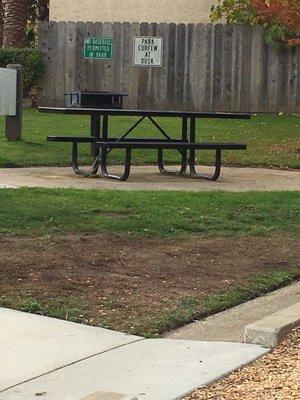 Two picnic tables and one small BBQ grill in the park