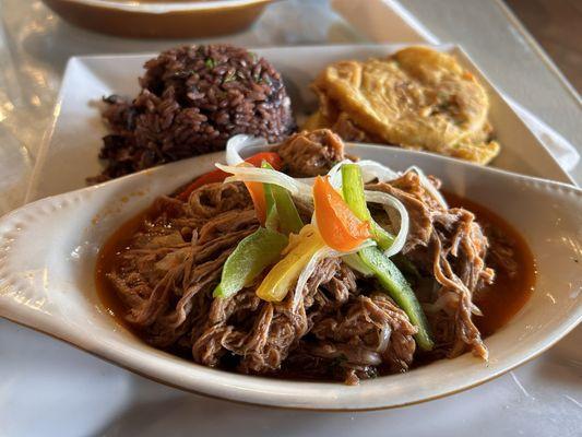 Ropa Vieja with one side of black beans and rice and a side of tostones