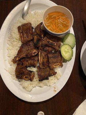 Bone in grilled beef short ribs with white rice, garnished with cucumbers.