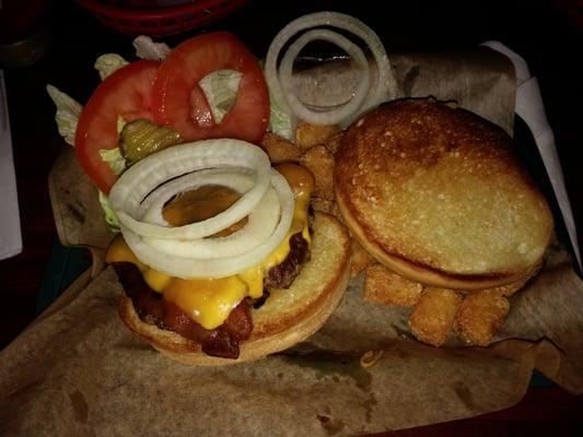 Bacon cheeseburger with tots and many toppings included on the side.