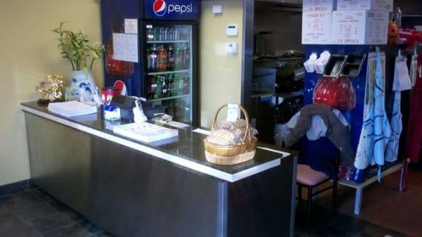 The front counter of the restaurant. Open and simple design, with a well-stocked drink fridge.