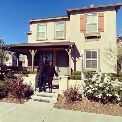 My husband and I joyfully standing in front of our new home.