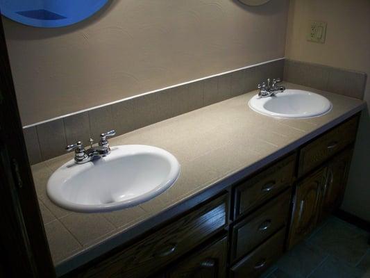 Refinishing turned a plain bath tile counter into a stone look.  The sinks were also given a fresh look with resurfacing.