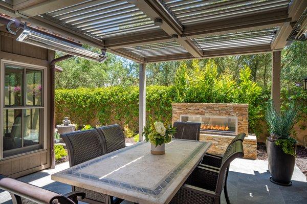 Dining area accented with fire feature and a patio cover with moving slats in this Santa Luz home