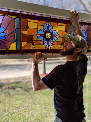 Installing a restored stained glass window sash in a Saint Paul home.