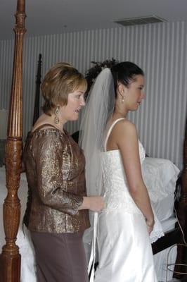 Owner Jeannette Lessa, dressing bride in one of her custom handmade dresses.