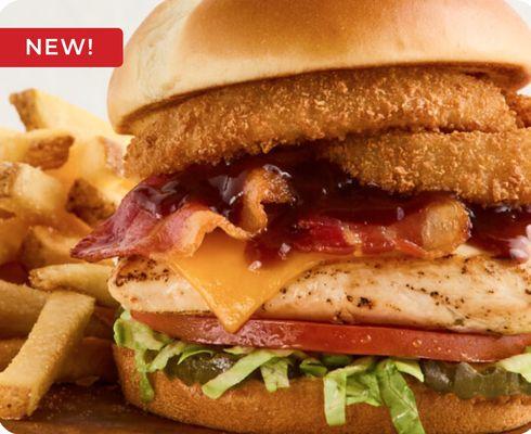 A smokehouse grilled chicken sandwich, barbecue sauce, bacon, cheddar cheese, and fried onion rings serve with daily fresh cut french fries