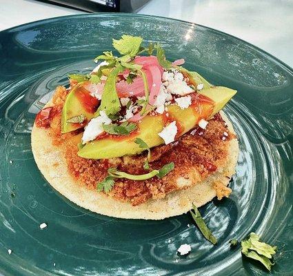 spicy crab cake tostada - made with macha butter and corn, topped with fresh cheese and avocado