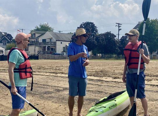 Three men on a beach w kayaks.