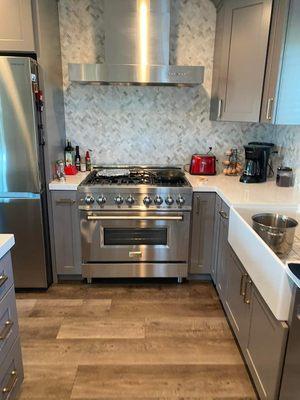 New range, hood, fridge, cabinets, counters, sink and backsplash.