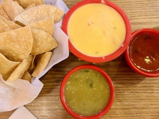 Homemade chips (I'm assuming, but they definitely taste like it), green & red salsa, & queso!