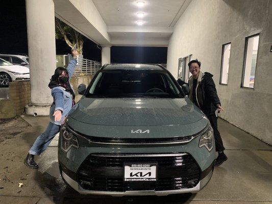 Two happy people standing next to new Kia Niro