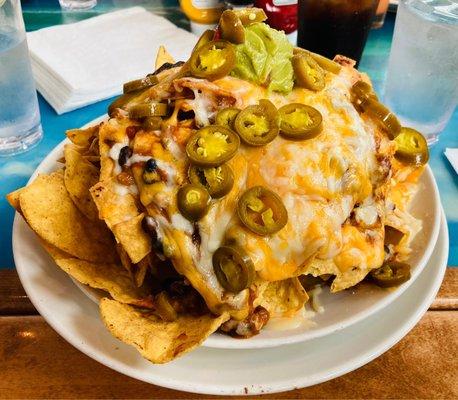 Volcano Nachos: Tortilla Chips with Chili, Fiesta Cheese, and Creamy Queso Sauce. Topped off with Jalapeños and Fresh Guacamole.