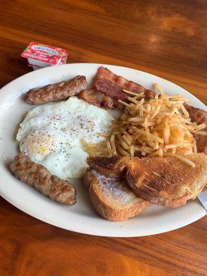 two eggs over medium, with a side of toast, hashbrowns, sausage, and bacon