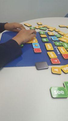 Second grade reading tutoring. The student is constructing sentences using a magnetic story board.