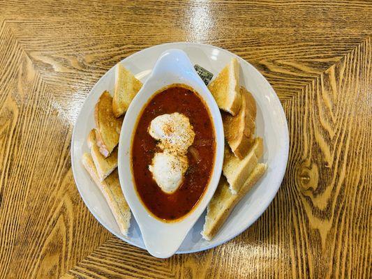 Enjoy SHAKSHUKA a simple yet flavorful combination of simmering tomatoes, onions, garlic, spices, and gently poached eggs.