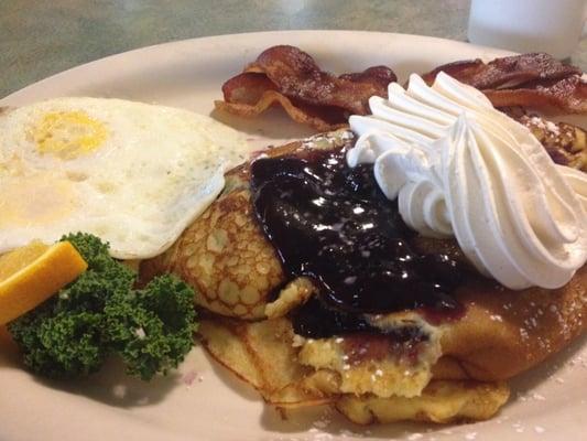 Blueberry Swedish pancake with side of eggs and bacon