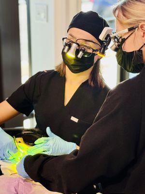 Precision teamwork! Dr. Regina and Iulia, donning dental loupes and focused light, work their magic on a comfy patient. ‍‍