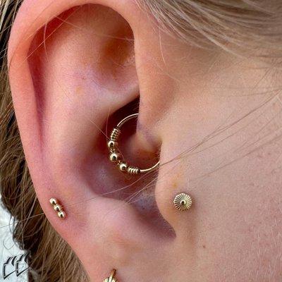 Ear Styling with tragus Daith and Mid Helix piercing with solid gold beaded designs at IRIS Studios Denver and Boulder