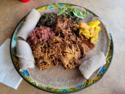 Fitfit, kitfo, gomen wot, salad green, tibs awase, alitkilt [cabbage & potatoes] on and surrounded by delicious injera