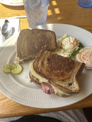 Rueben with thousand island in the side with potato salad