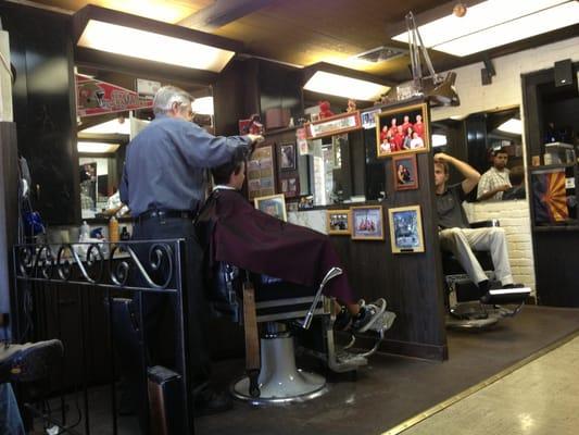 Old style (no pun intended) barber with good 'ol country music in the background. And a chair with razor strap! My kinda barber!