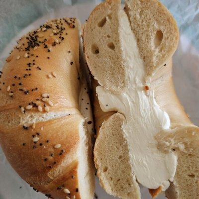 Cream Cheese on Everything Bagel. Uneven distribution of cream cheese on old bagel.