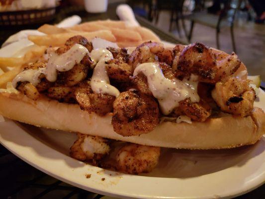 Blackened shrimp po boy sandwich with fries.