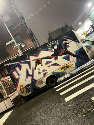 Truck with cool graffiti parked in the front of the bar