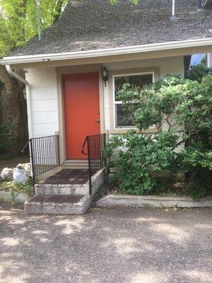 Office back door entrance. A couple steps up to a the red entrance door.