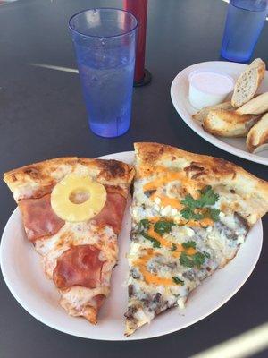 One slice of Hawaiian and "Taco Truck Pizza" with dipsticks (bread sticks) in the background.