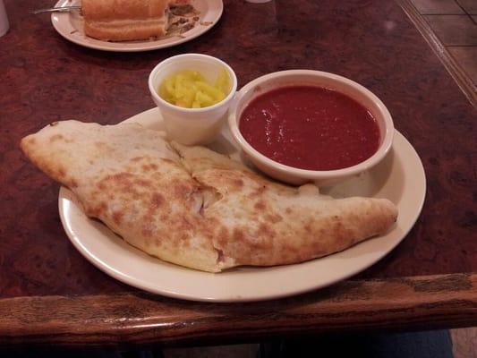 Calzone with banana peppers on the side and marinara sauce