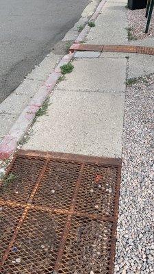 Walkway full of gravel, obstacles, and rusted grates - outdated at best