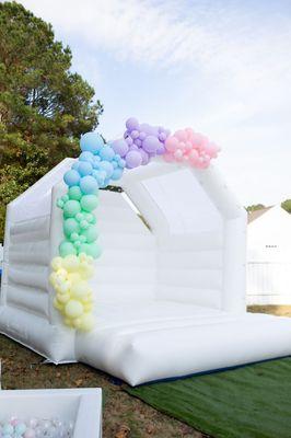 White bounce house rental with balloon garland