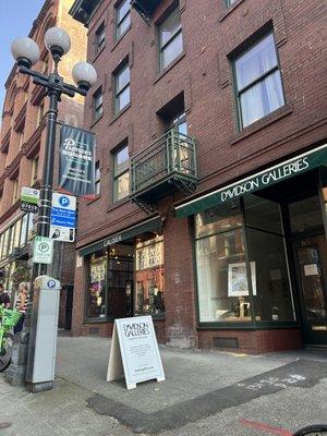 View of gallery exterior from street with sidewalk sign