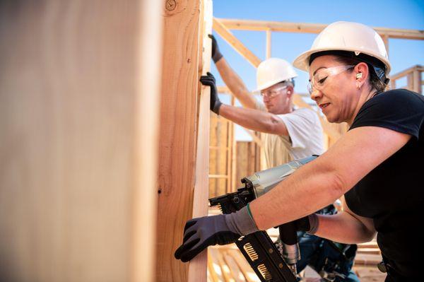 Framing and lumber being held up by Builders FirstSource employees at constriction site.