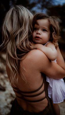 A mommy and me moment as her daughter cuddles up in her arms.